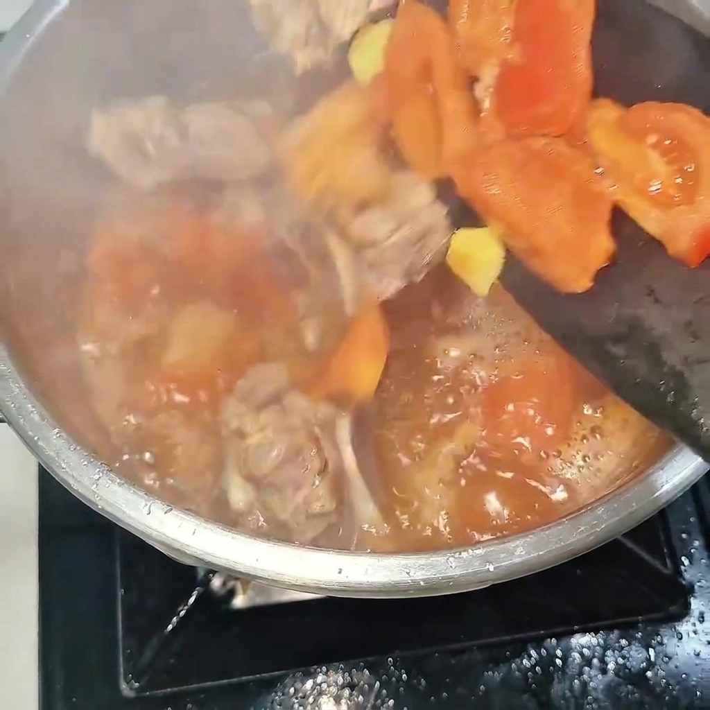 The beef ribs and tomato mixture being poured into a steel pressure cooker, ready for the lid to be secured.