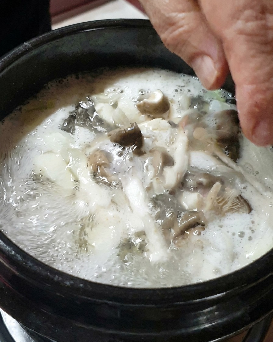 Chopped onions and sliced mushrooms being added to the stew.