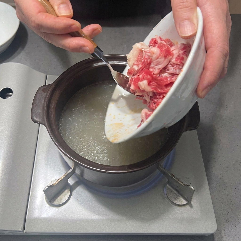 Fresh beef brisket slices being added to the pot of seasoned water.