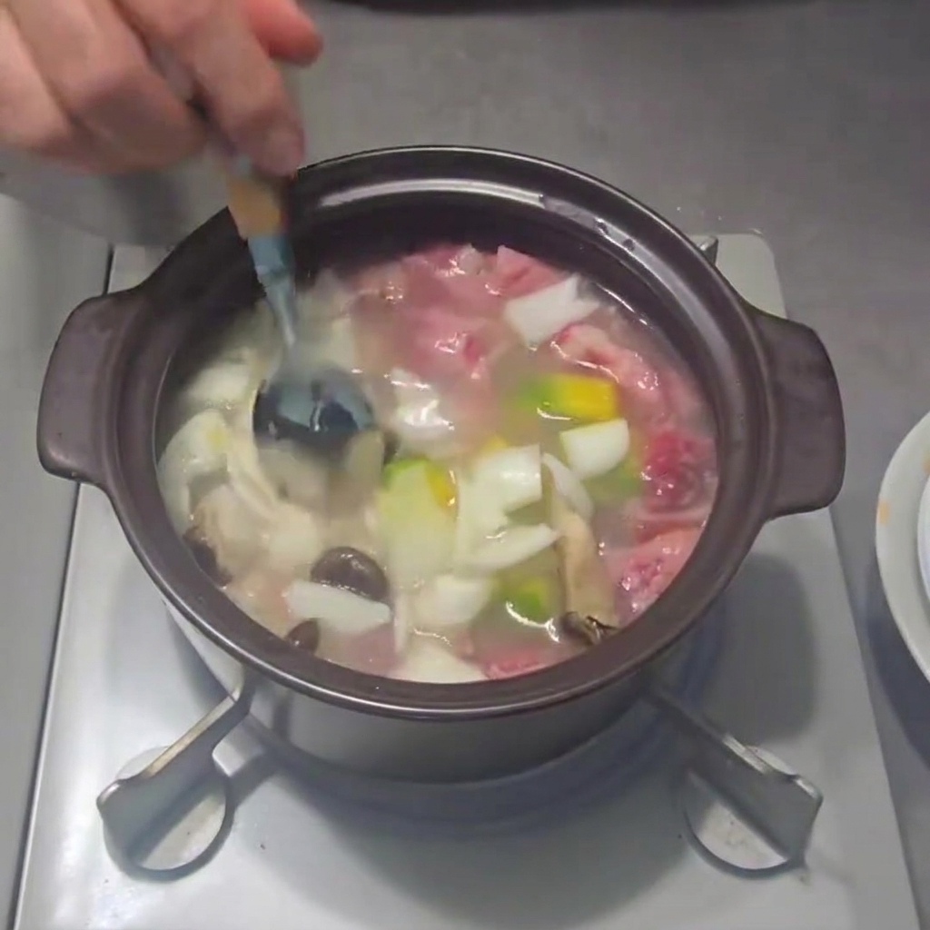 Green onions being sprinkled into the pot of stew.