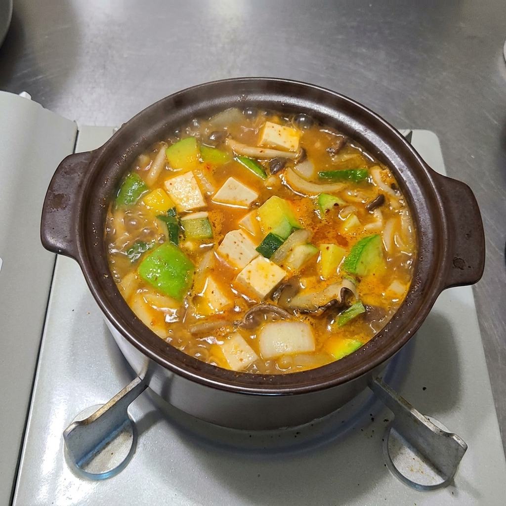 Thinly sliced red and green chilies being scattered across the surface of the bubbling stew.