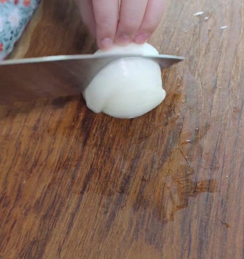 Small, diced onion pieces on a wooden cutting board, ready for the pot.