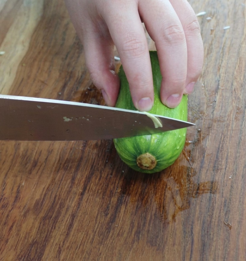 Freshly sliced triangular pieces of zucchini on a wooden cutting board.