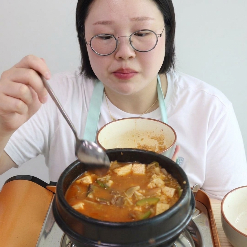 Cooked white rice being stirred into the thick, bubbling stew in the pot.
