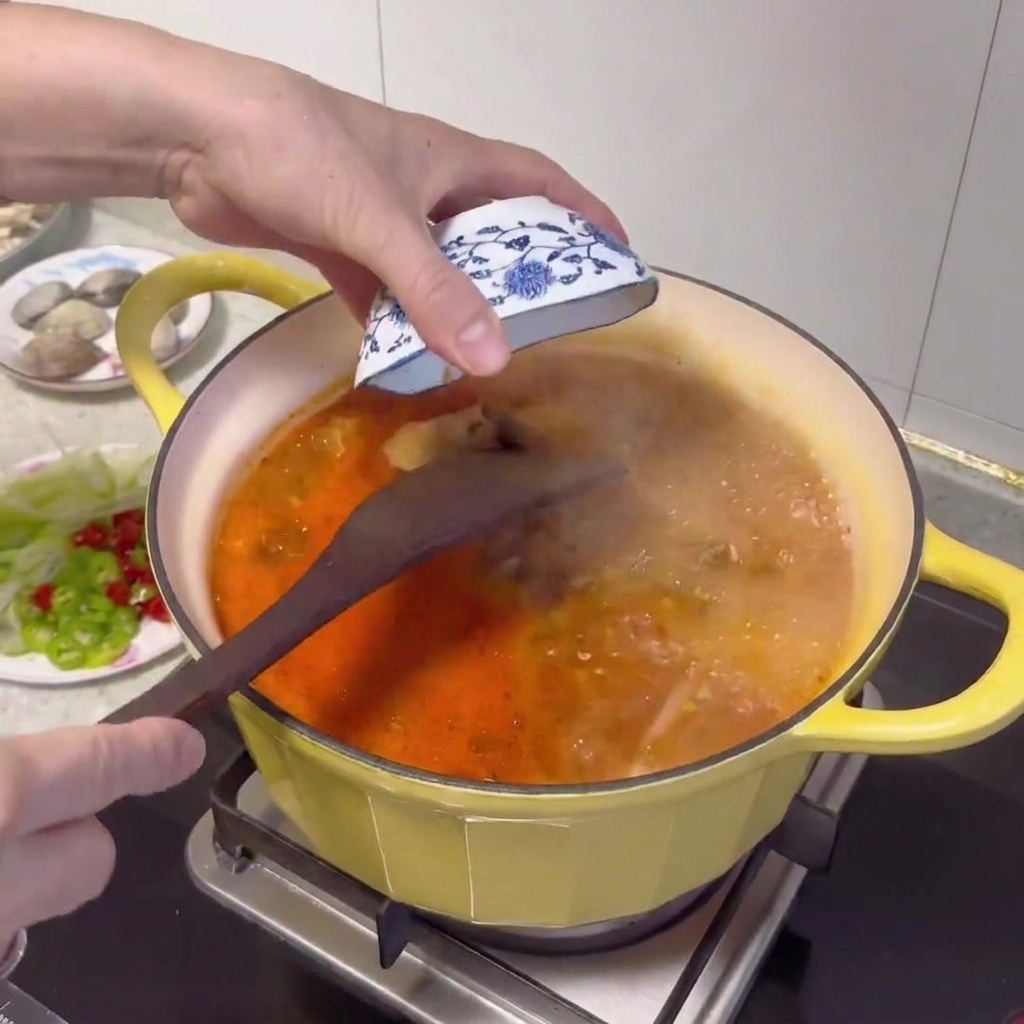 A wooden spoon adding a dollop of Korean soybean paste into the bubbling broth.