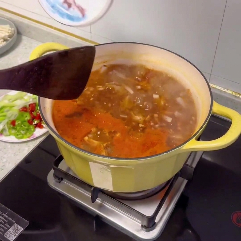 Various sliced vegetables and clams being added to the pot of beef soybean paste stew.