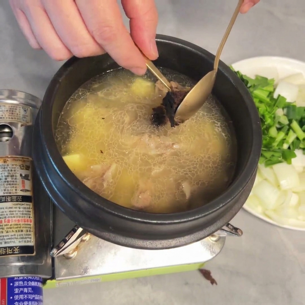 A spoonful of thick, aged soybean paste being stirred into the soup.