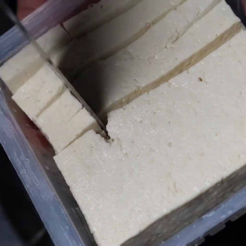 Bite-sized cubes of white tofu being added to the simmering stew.