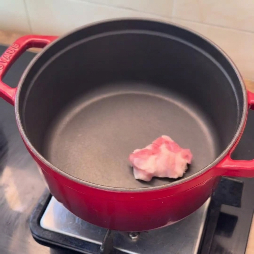 Pork belly slices, onion wedges, and minced garlic ready in a preheated red pot.