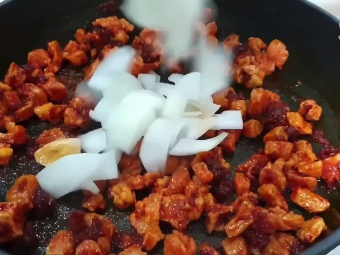 Diced onion, green onion, and garlic added to the pan with the cooking pork.