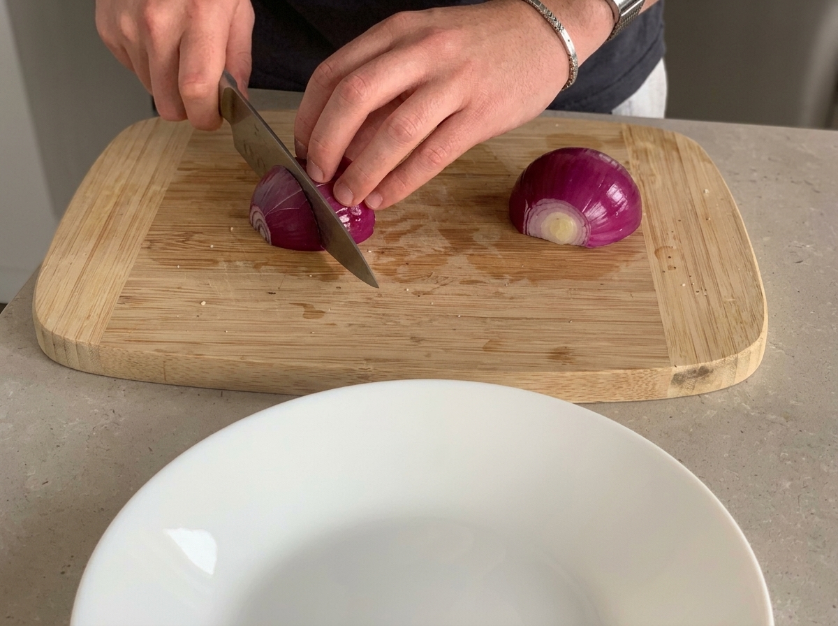 Red onion being chopped into small pieces on a wooden cutting board.