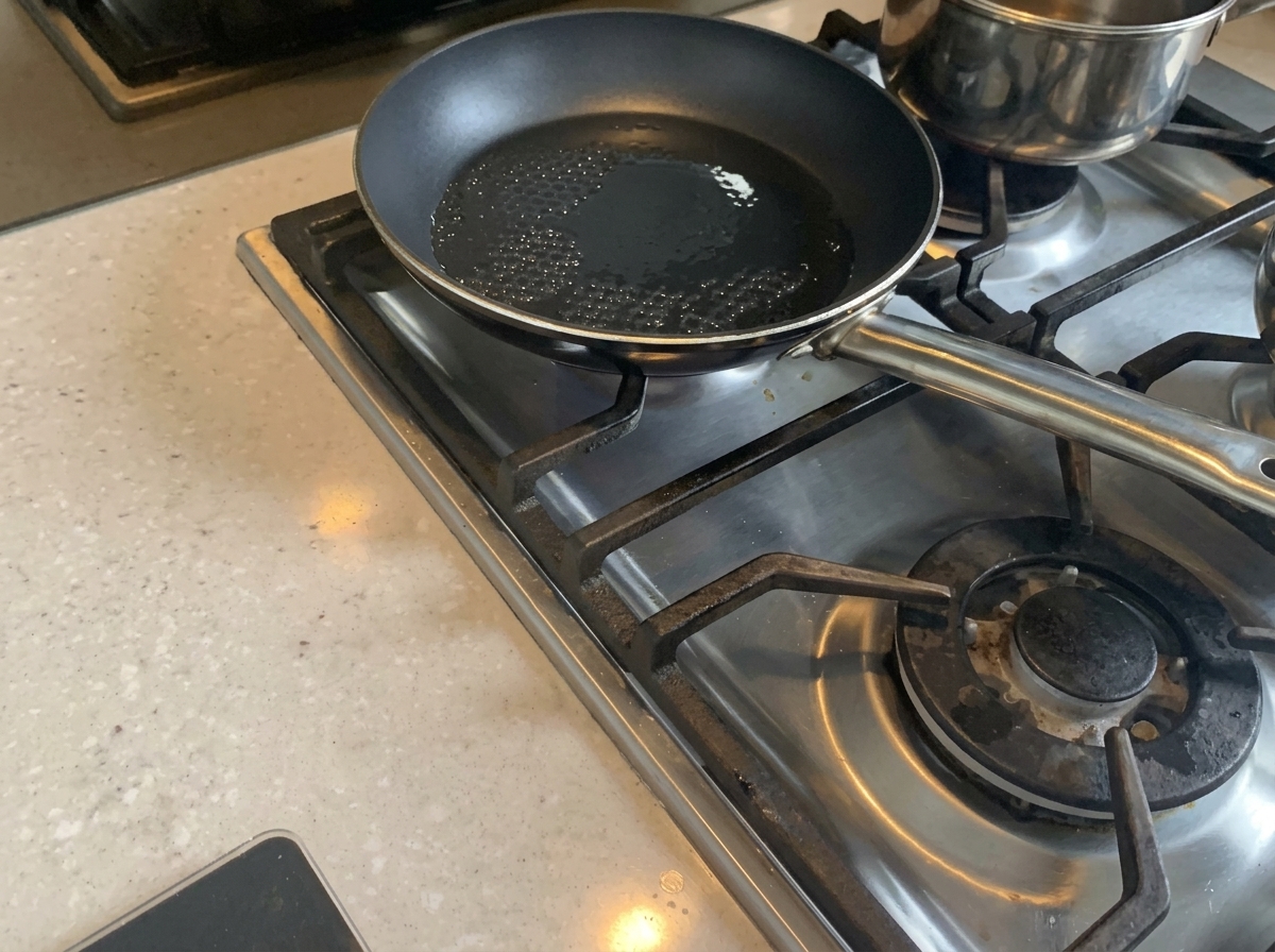 Chopped onions being stir-fried in a pan with hot oil until softened.