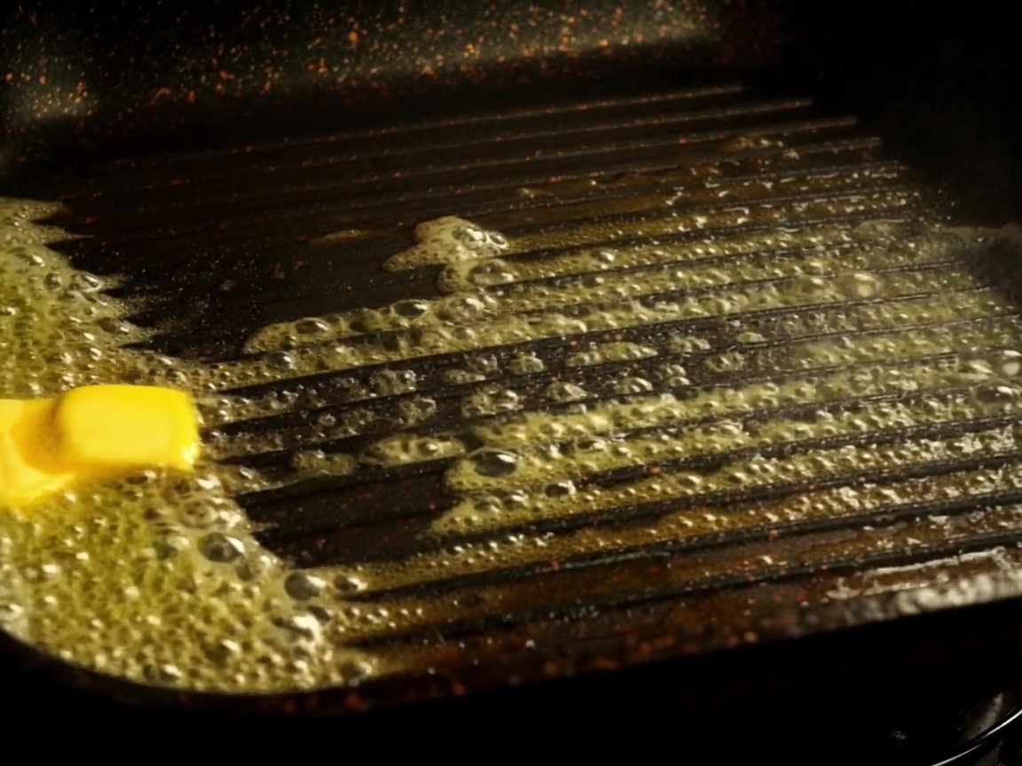 Burger bun halves toasting in a grill pan with melted butter.