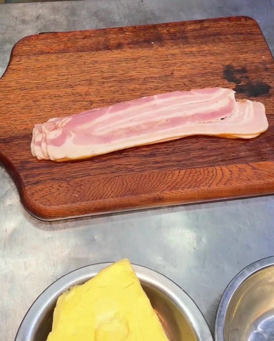 Pieces of sliced smoked bacon resting on a wooden cutting board.