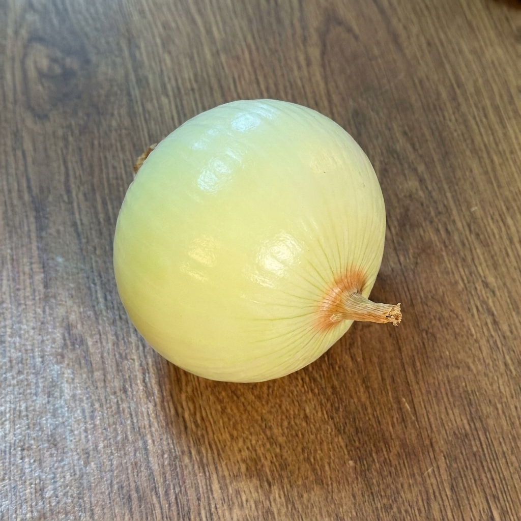 A peeled, whole onion resting on a wooden surface.