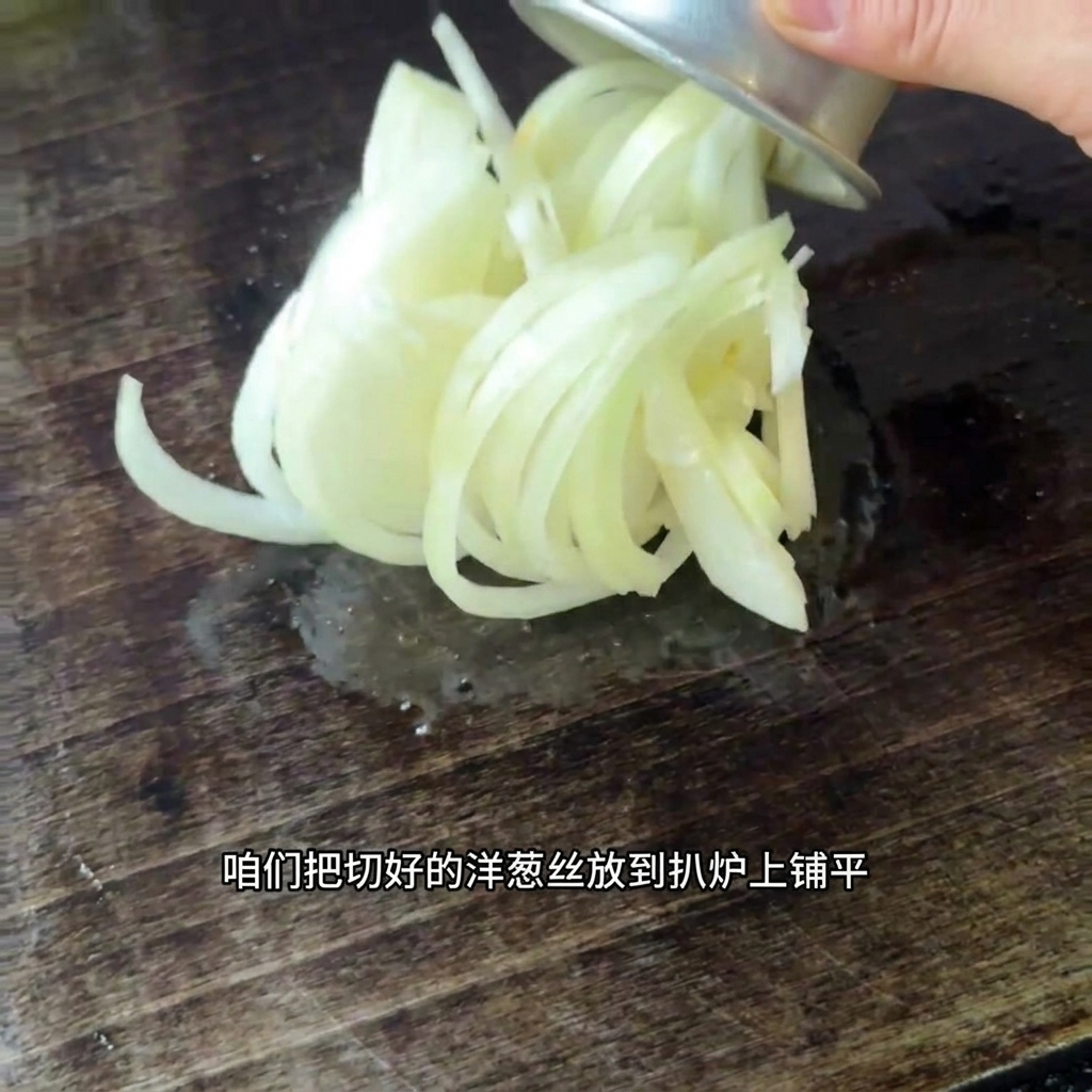 Freshly sliced onions being spread across a hot griddle surface.