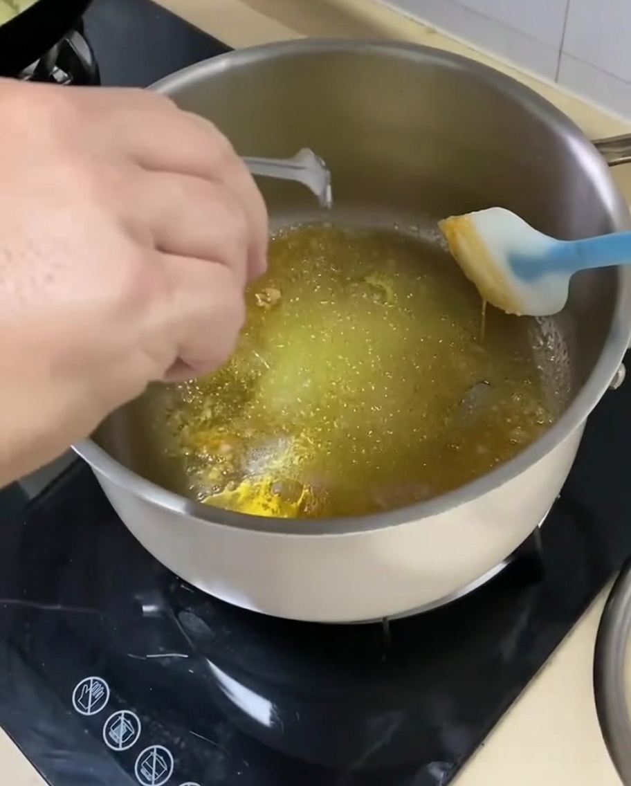 Sliced onions being added to the pan with caramelized sugar and seasonings.