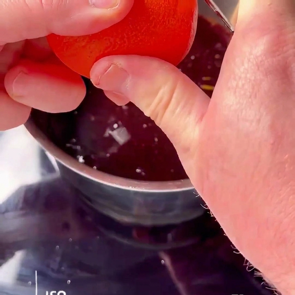 Fresh orange juice being squeezed into a simmering red cherry sauce.