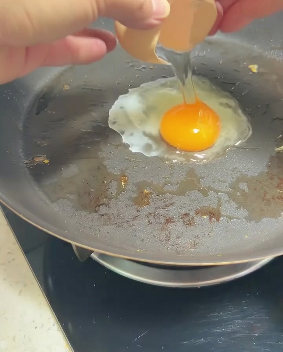 A single egg frying in a pan with a golden yolk.