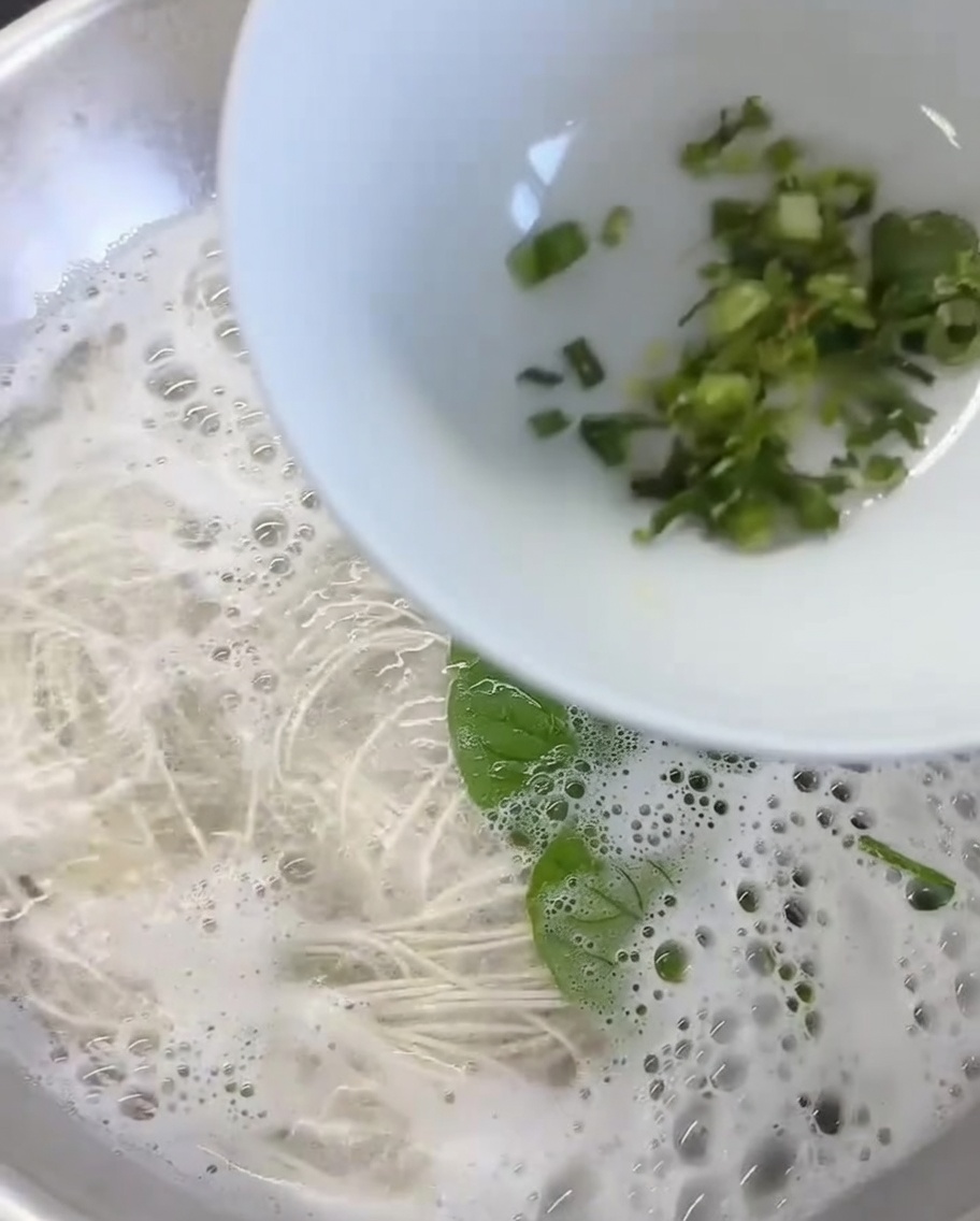 Minced ginger and chopped cilantro resting at the bottom of a white serving bowl.