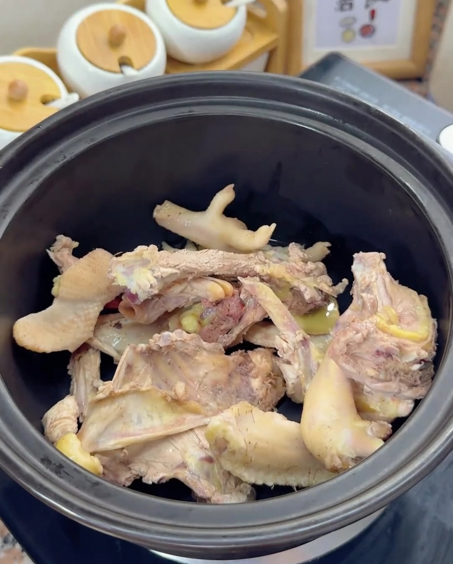 Blanched chicken bones resting at the bottom of a black clay pot.