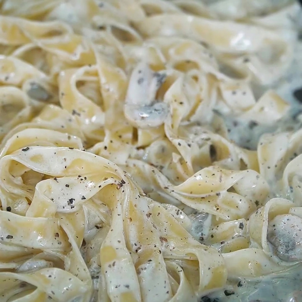 Salt and freshly cracked pepper being sprinkled over the creamy truffle pasta.