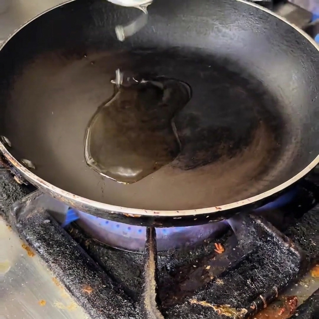 Onion, garlic, bacon, mushrooms, and asparagus pieces being stirred in a hot oiled frying pan.