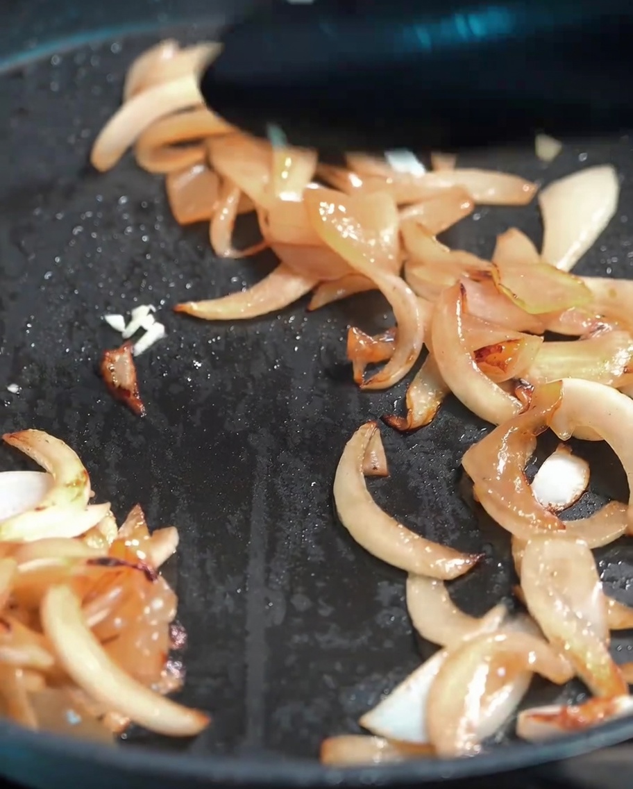 Fresh minced garlic being mixed into the soft sautéed onions.