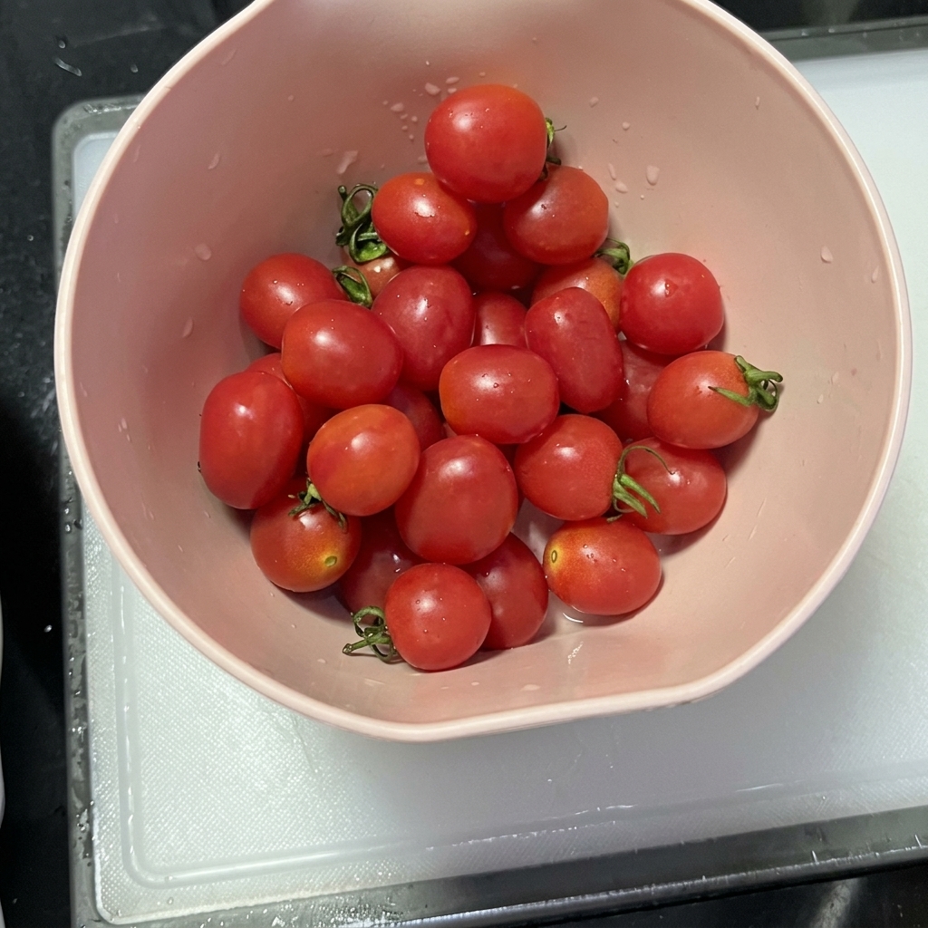 Halved cherry tomatoes laid out on a clean cutting board after being sliced.