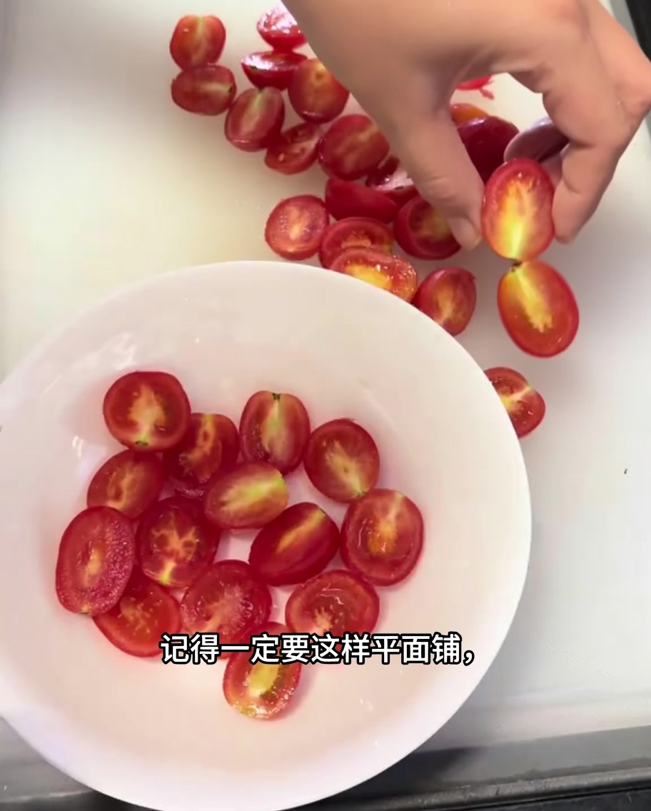 A close-up of halved cherry tomatoes neatly arranged in a single layer in a white bowl.