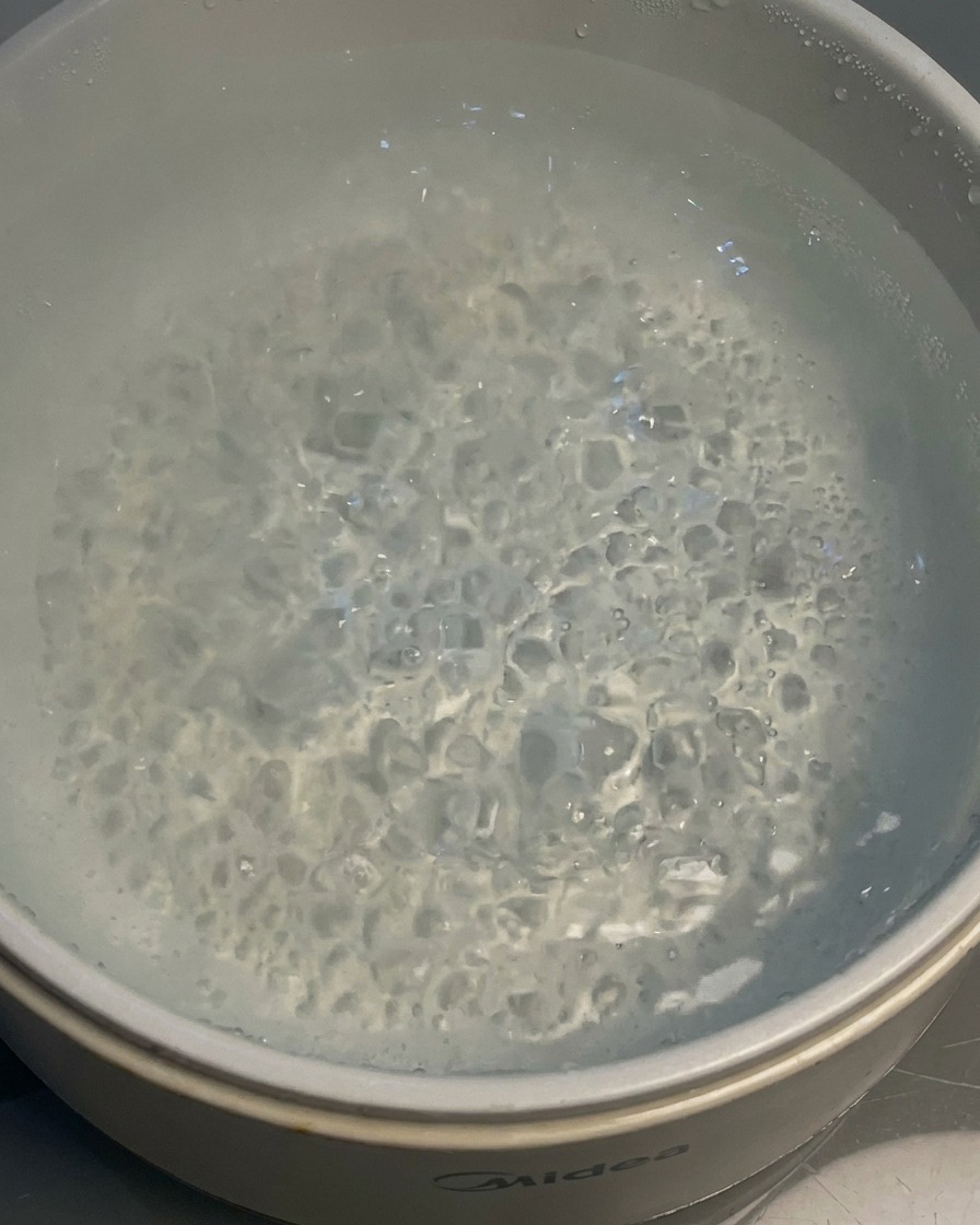 Noodles cooking in a pot of boiling water.