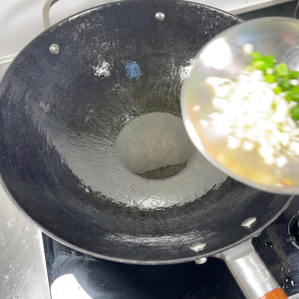 Chopped green onions and minced garlic being added from a ladle into a hot wok with oil.