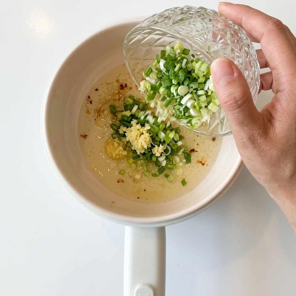 Chopped green onions being poured into the pot with sautéed garlic.