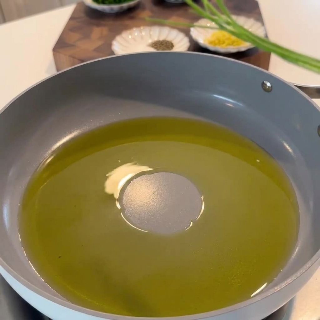 Parsley stems, lemon zest, and chili flakes being sautéed in a pan with garlic-infused olive oil.