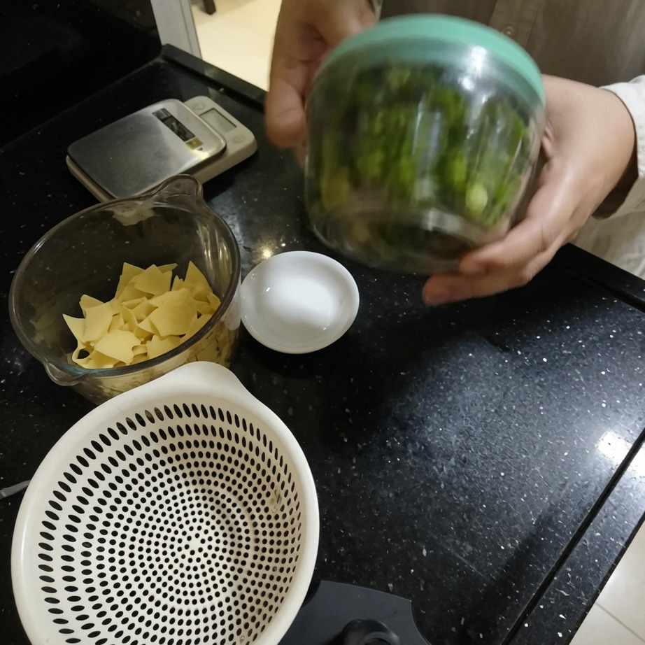 A hand operating a string-pull food processor to mince herbs.