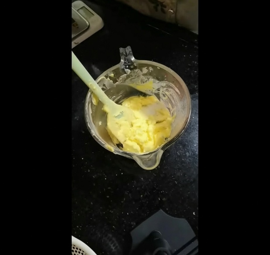 The minced green herb mixture being transferred into a bowl of soft yellow butter.