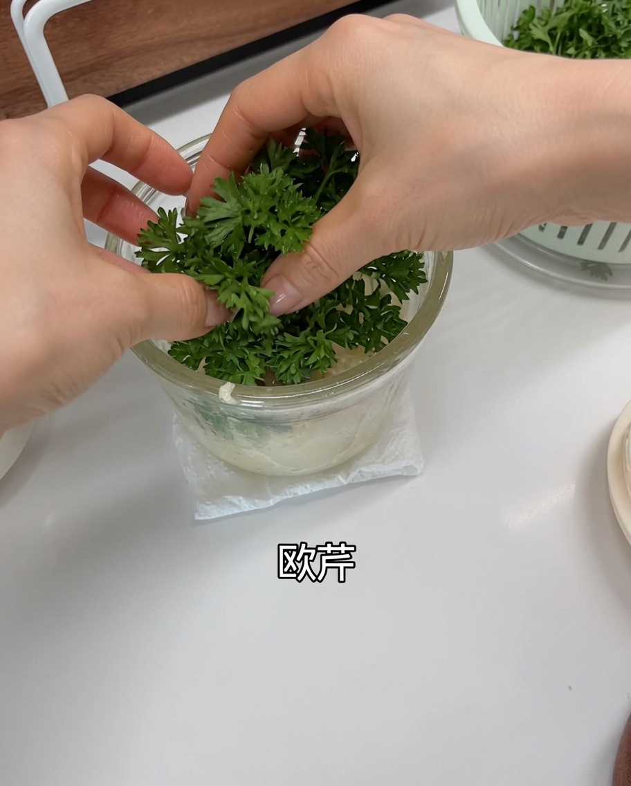 Fresh green parsley leaves being placed into the food processor over the garlic and shallots.