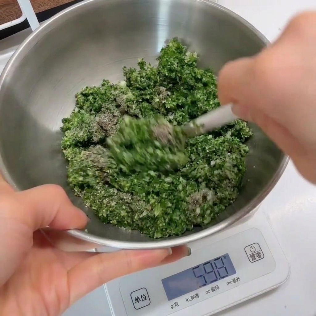 A close-up of the green herb mixture being stirred in a stainless steel bowl with a white spatula.