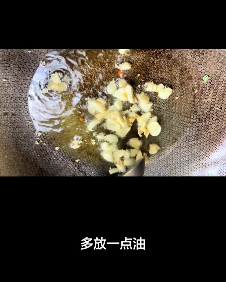 Slices of garlic frying in hot oil in a seasoned wok.