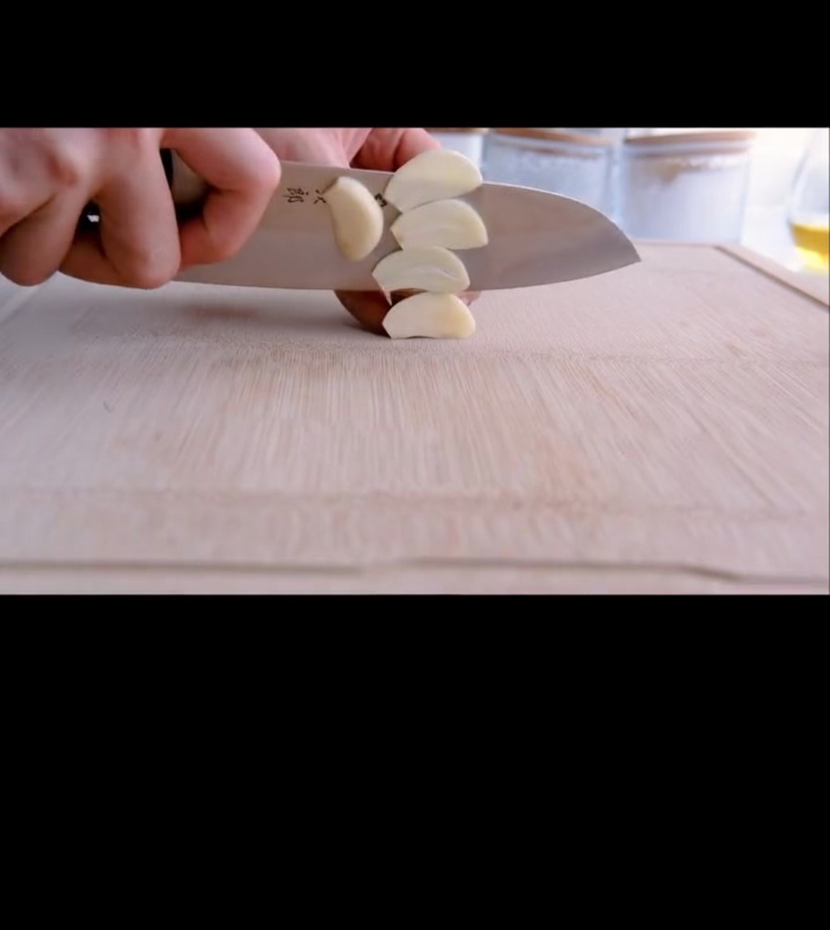 Dried red chili peppers being cut with kitchen shears into a small bowl.