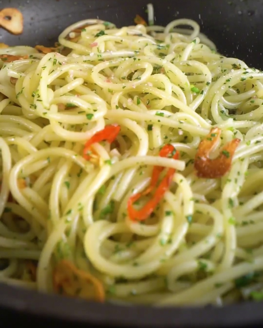 Salt and freshly ground black pepper being sprinkled over the pasta dish in the pan.