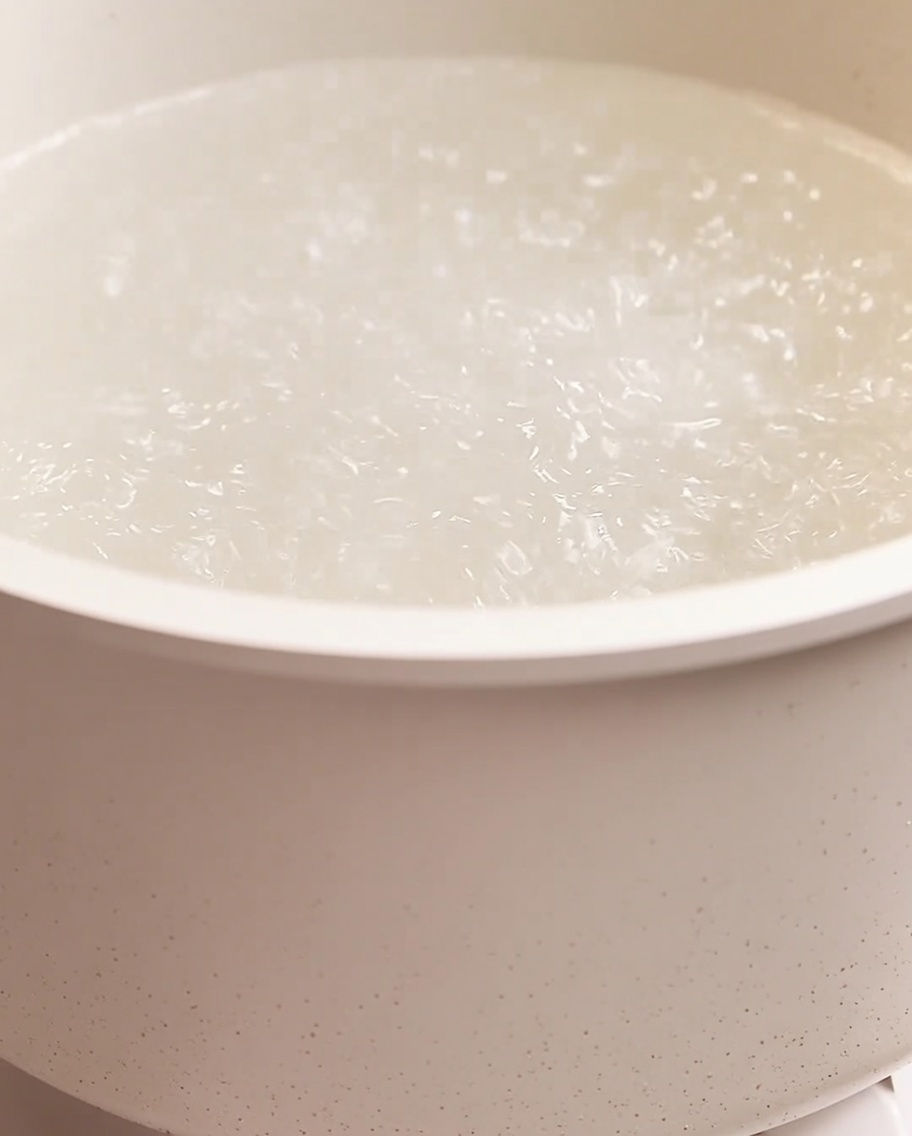 Spaghetti cooking in a large pot of boiling water with visible bubbles.