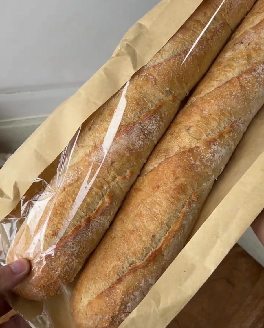 Diagonal slices of baguette arranged on a cutting board, ready for the garlic butter mixture.