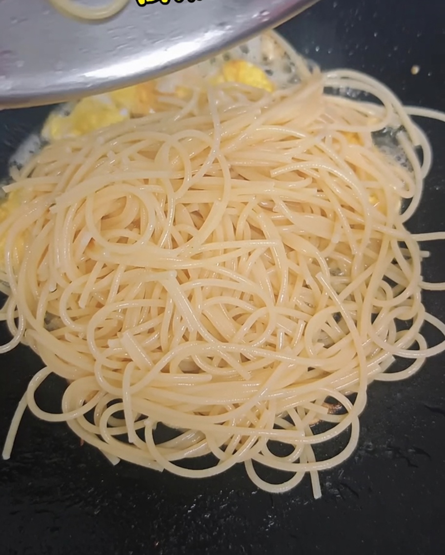 Blanched broccoli florets and halved cherry tomatoes added to the wok with spaghetti and eggs.