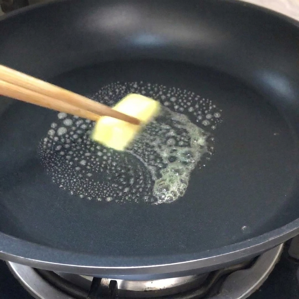A knob of butter melting in a hot pan.