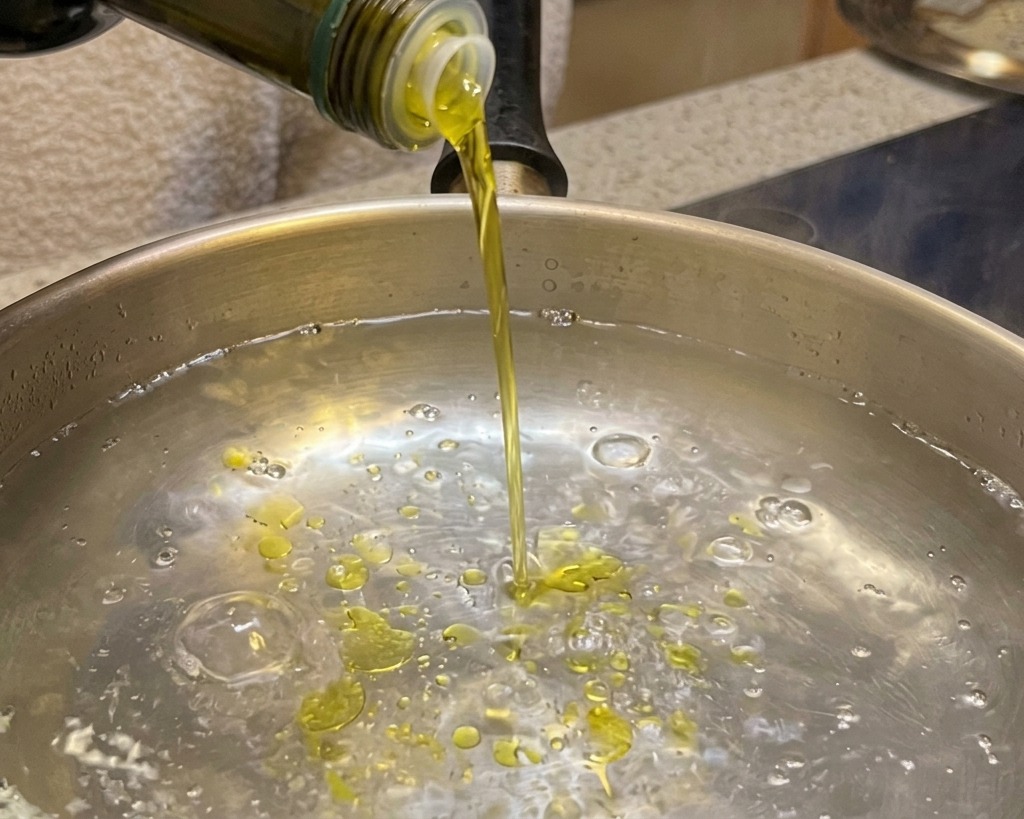 Pouring olive oil into a pot of boiling water.