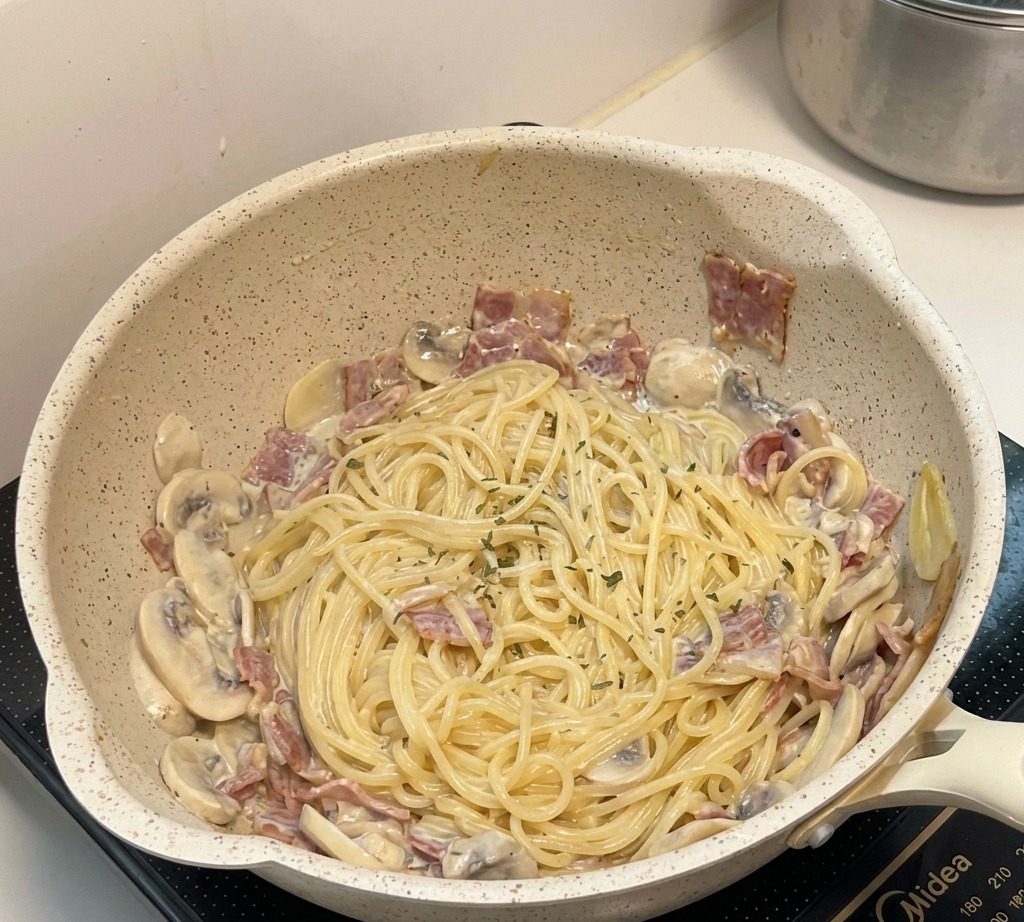 Final creamy mushroom pasta dish in the pan, garnished with herbs and ready to serve.
