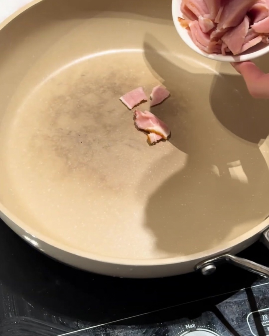 Lean bacon pieces sizzling in a hot, dry pan, starting to render their fat.