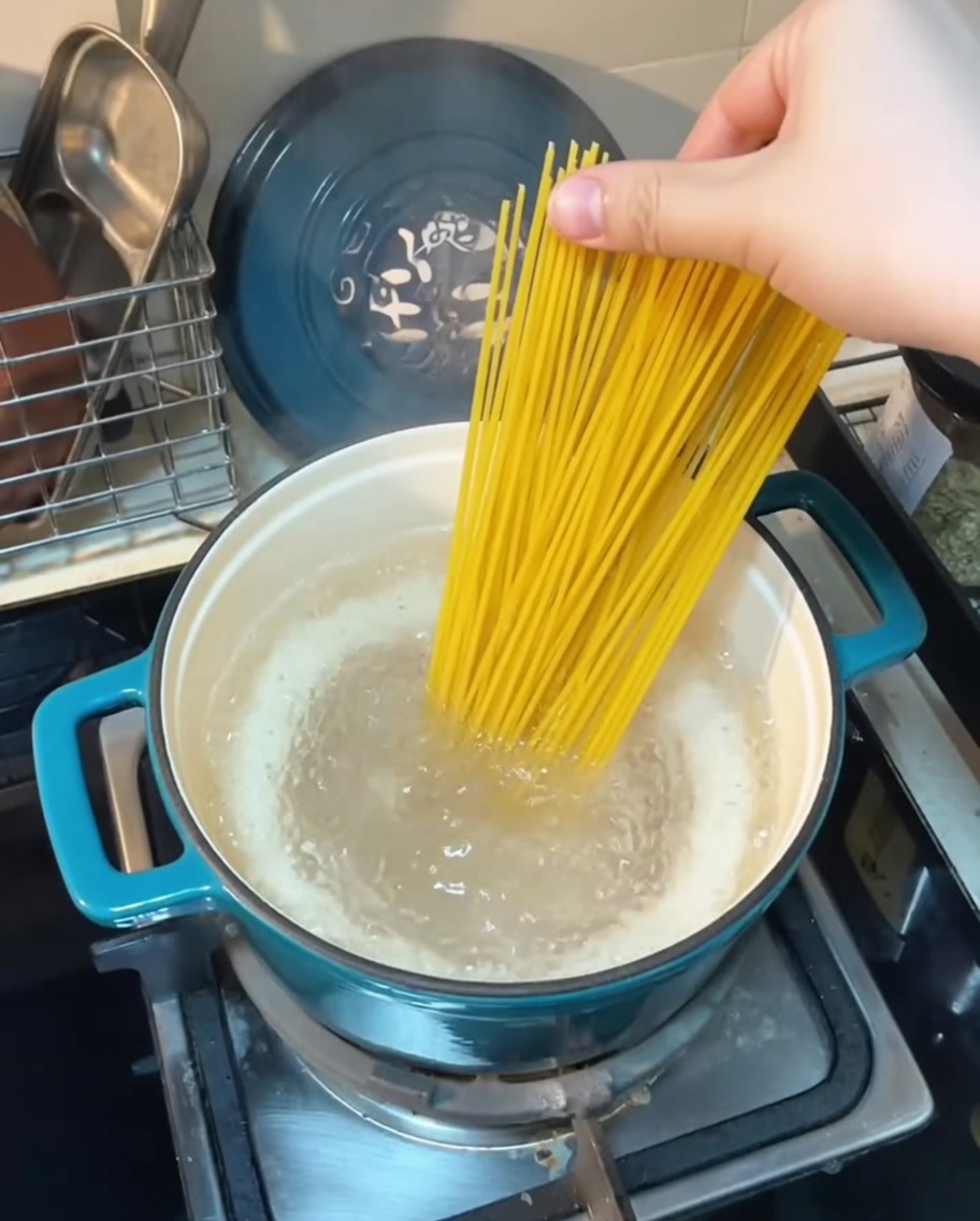 Spaghetti strands being lowered into a pot of boiling water.