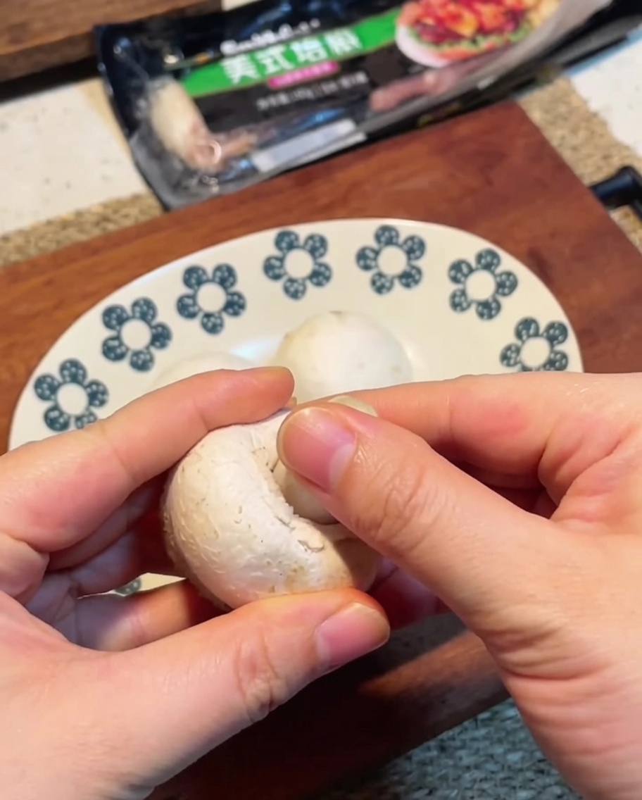 Thinly sliced white button mushrooms on a wooden cutting board.